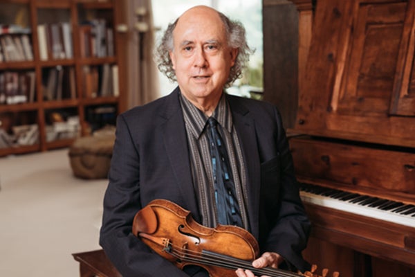 Edelberg with violin sitting in front of piano in a study