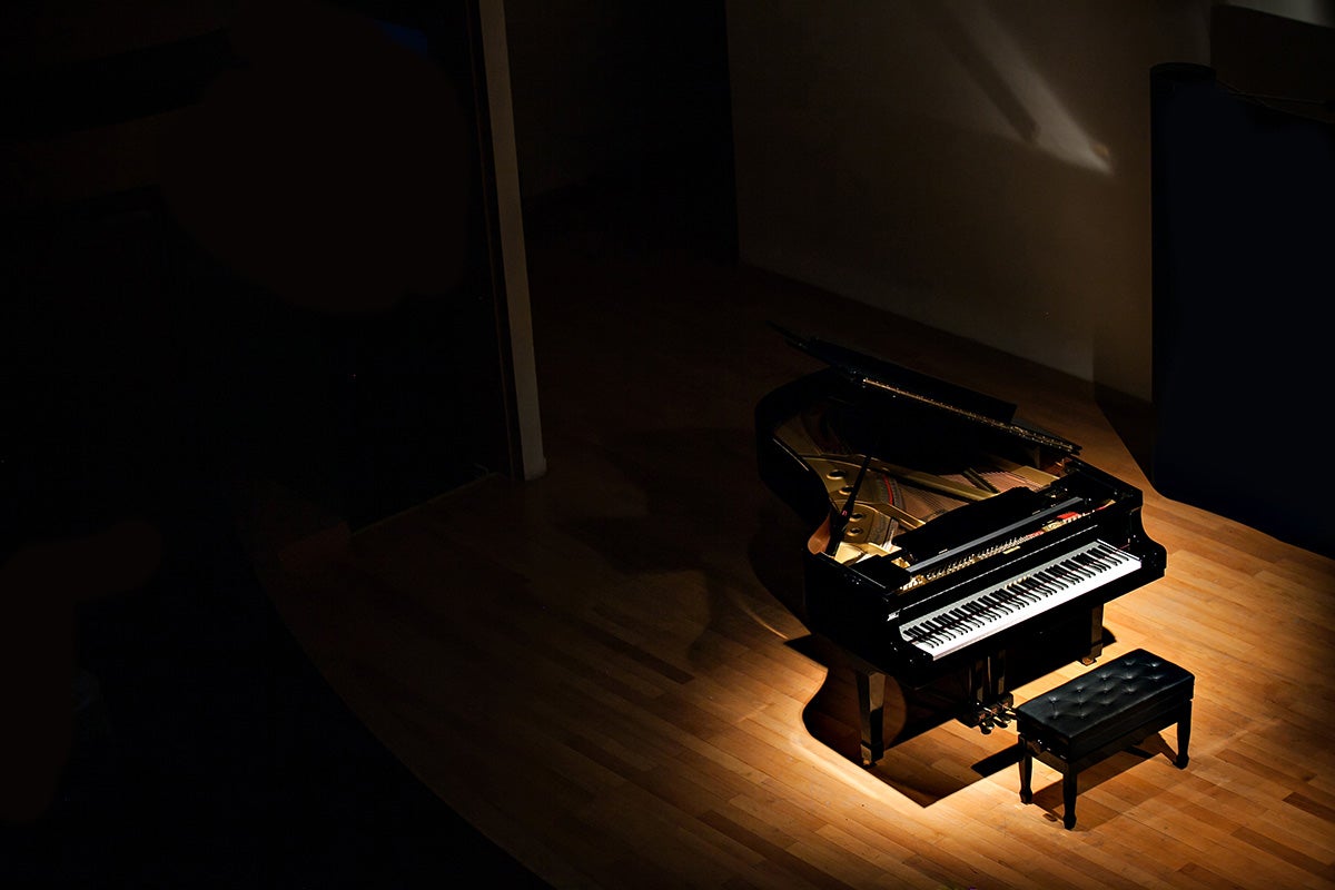 black grand piano at spot light in dark room