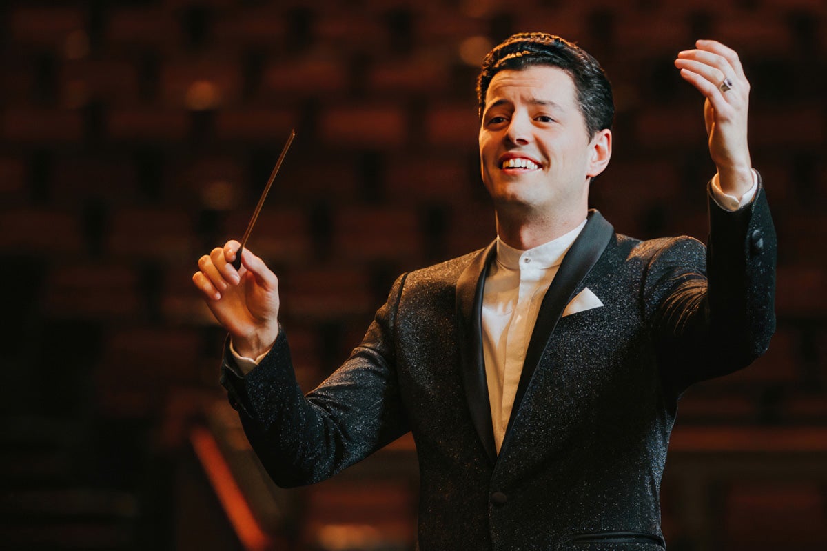 Troy Quinn with baton smiling as he conducts