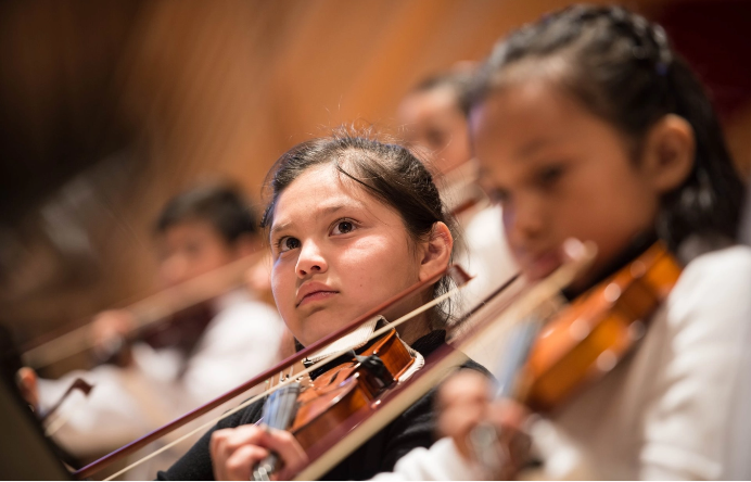 Youth violin player and other youths in soft focus around her
