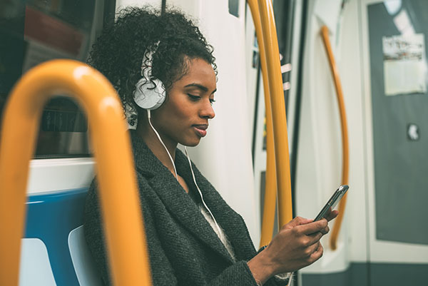 Woman wears headphones, listens to music on public transportation.
