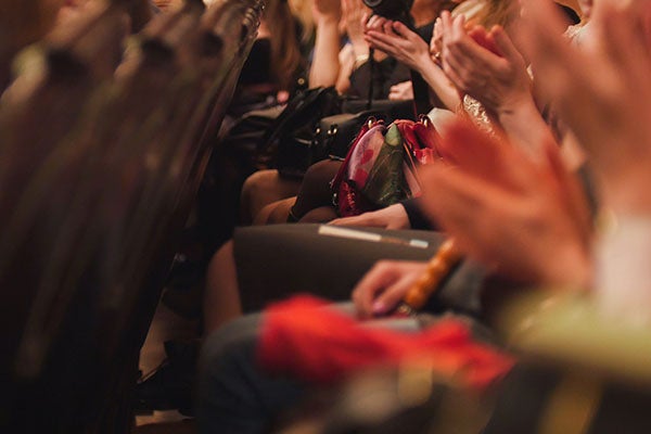 Hands of spectators applauding at a performance hall.