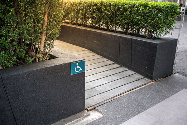 Ramp outside a venue with wheelchair access symbol on planters.
