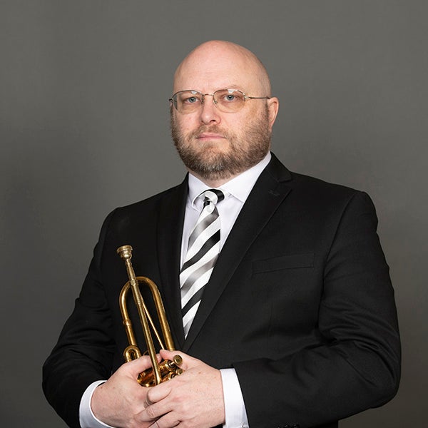 A portrait of Kale Cumings and his horn