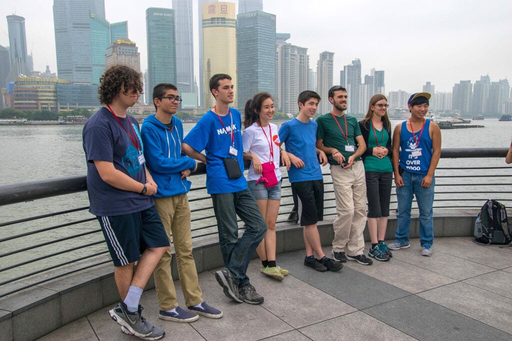 group shot of students against a rail in front of water and buildings