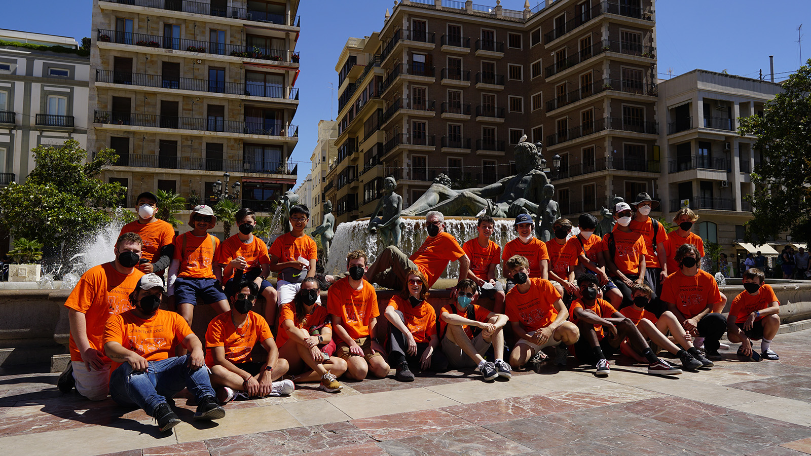 SYO in orange shirts for a group shot by a fountain
