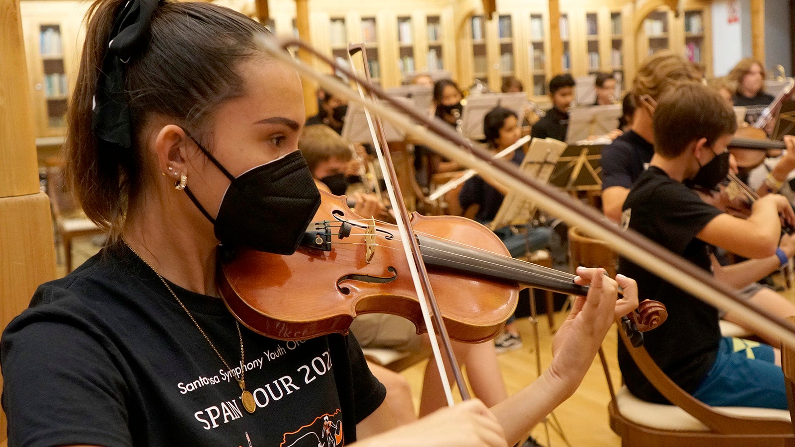 Young woman practicing violin in rehearsal