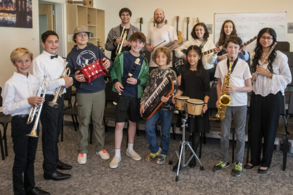 Kids in a music room with their instruments, smiling