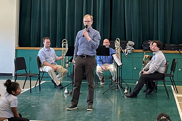 A music teacher speaks in an auditorium to young musicians